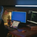Woman using multiple screens for cybersecurity tasks in a cozy home office