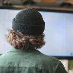 person in green shirt wearing black knit cap