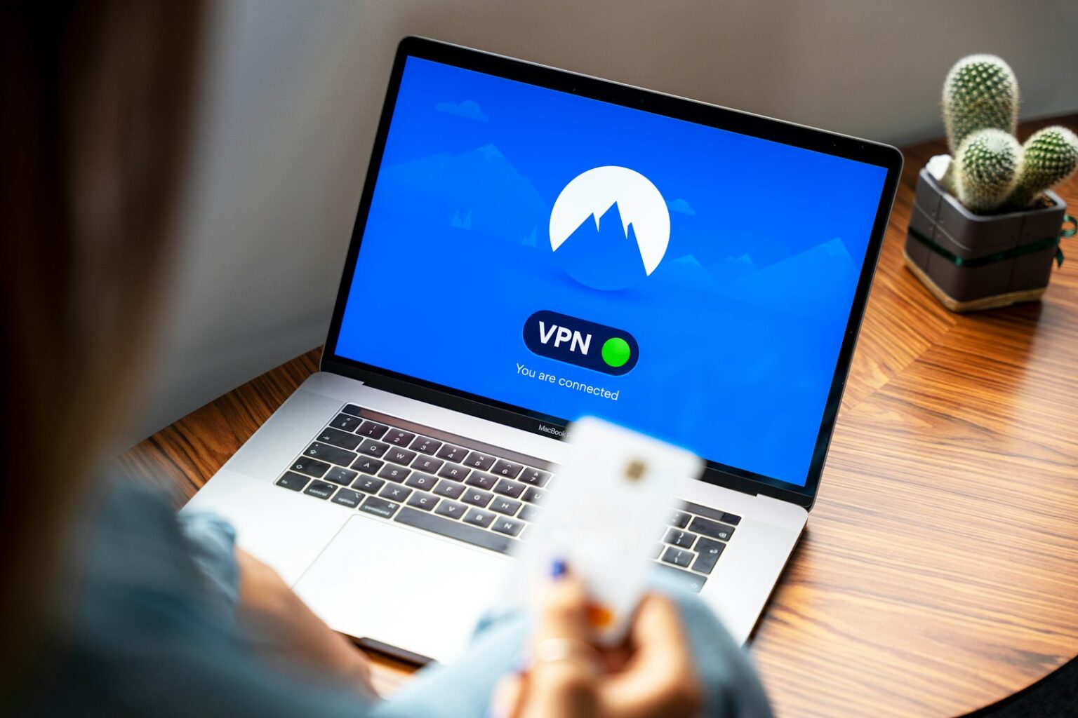 macbook pro on brown wooden tablewith logo of nordvpn