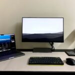 a desk with a laptop, keyboard, mouse and monitor