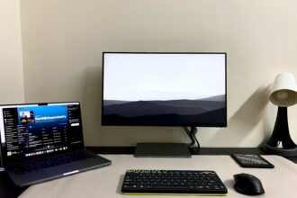a desk with a laptop, keyboard, mouse and monitor