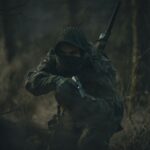 person in black and white hoodie holding rifle