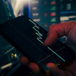Trader analyzing stock market data on smartphone and phone