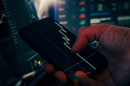 Trader analyzing stock market data on smartphone and phone