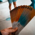 person holding brown, blue, and white tickets