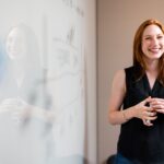 woman in blue tank top standing beside white wall