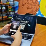 a person using a cell phone while sitting in front of a laptop