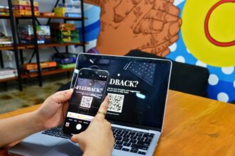 a person using a cell phone while sitting in front of a laptop