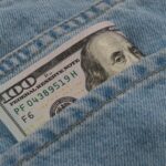 a hundred dollar bill sticking out of the back pocket of a pair of jeans