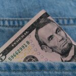 a dollar bill sticking out of the back pocket of a pair of jeans