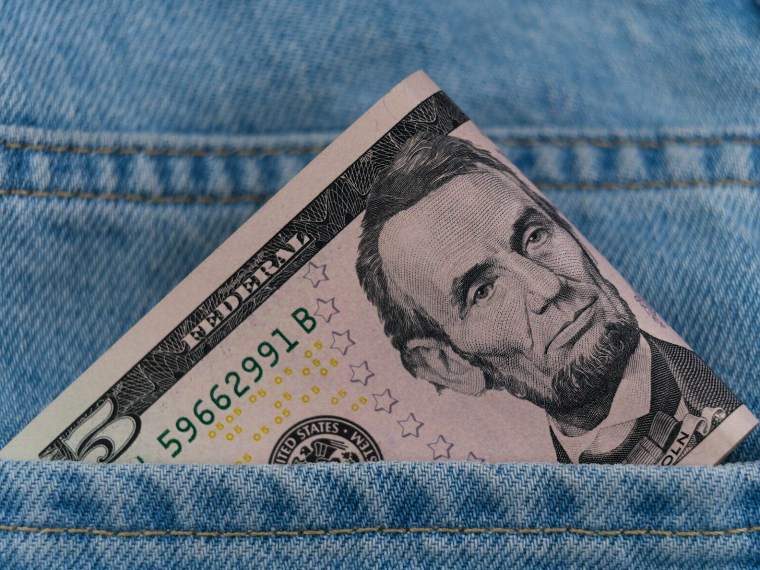 a dollar bill sticking out of the back pocket of a pair of jeans