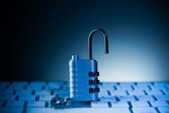 An unlocked padlock rests on a computer keyboard.