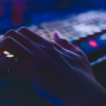 A hand typing on a glowing keyboard in dim lighting, perfect for tech themes.